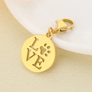 Close-up of golden hollow pendant with LOVE letters and paw print on white ceramic tray