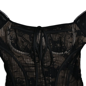 Détail de robe courte en dentelle noire avec bustier style corset et laçage au col