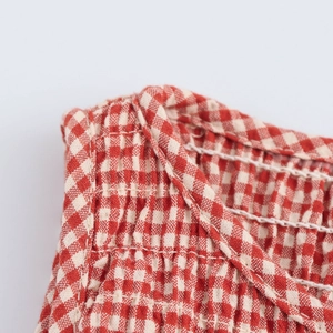 Detailed close-up of red and white checkered fabric with fine stitching and pleats
