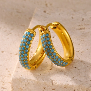 Gold hoop earrings with turquoise bead inlay shown on a natural stone background