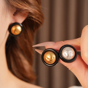 Macro view of round pleated stud earrings in gold and silver textured metal finishes