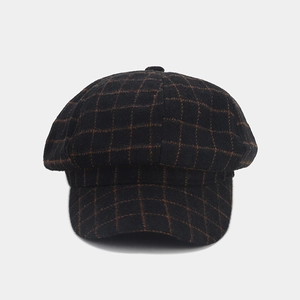 Detail of vintage autumn newsboy cap featuring black and orange plaid wool texture