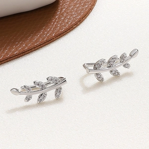 Elegant silver leaf ear cuffs with sparkling crystals on a minimalist background