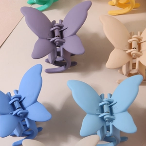 Detail view of matte butterfly hair clips in various pastel macaron colors with metal springs