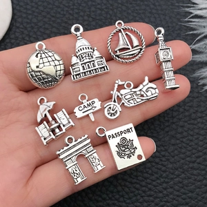 Set of nine silver alloy travel themed charms including passports and globes on hand