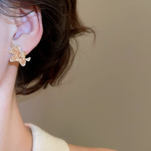 Close-up of elegant unicorn stud earring with champagne resin and sparkling crystals