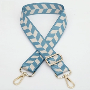 Detail of blue and beige woven shoulder strap with gold metal buckle and adjusters