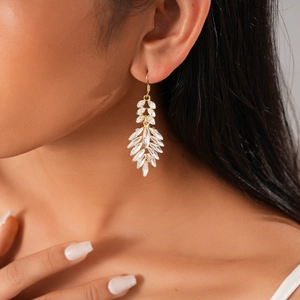 Macro detail of elegant leaf-shaped drop earrings with marquise-cut crystals on model