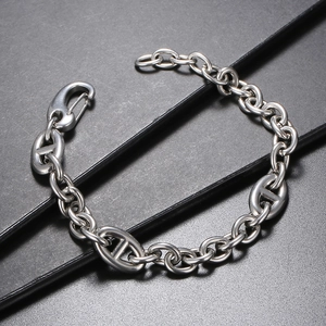 Close-up of polished silver anchor chain bracelet on a black textured background