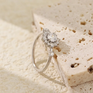 Macro shot of silver floral ring with round halo zircon on beige travertine stone