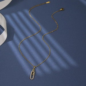 Collier doré avec pendentif double anneau serti de zircons sur fond bleu texturé
