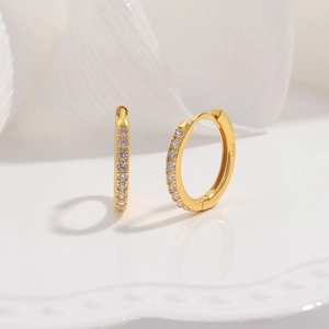 Macro detail of gold S925 sterling silver hoop earrings with cubic zirconia inlay stones