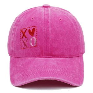 Dettaglio ravvicinato del ricamo XOXO e del cuore sul berretto da baseball rosa.