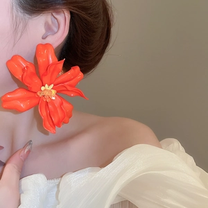 Detailed view of oversized orange acrylic flower earrings with vibrant glossy finish