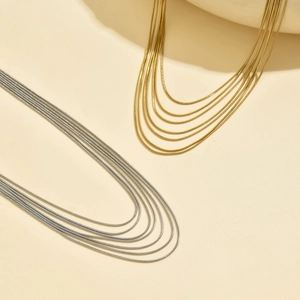 Dettaglio della collana a catena a serpente multistrato in oro e argento con texture elegante