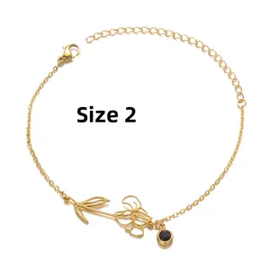 Close-up of No. 2 gold birth flower bracelet with a dark gemstone and adjustable chain