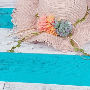 Close-up of pink woven sun hat featuring 3D floral accents and wavy scallop edges