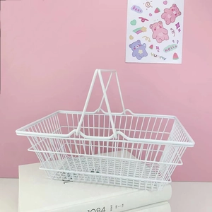 White minimalist metal mesh storage basket with double handles on a pink background