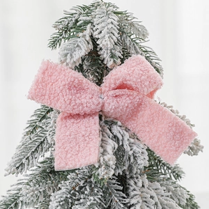 Pink plush ribbon bow topper on a snowy Christmas tree for festive decoration