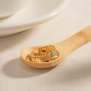 French vintage gold rings set with a round green gemstone on a natural wooden background
