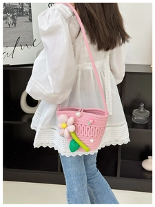 Pink woven crossbody bag with pearl flowers worn by a model in a casual setting