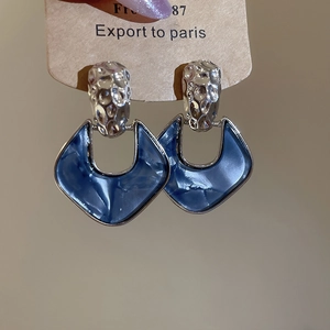 Detailed macro of silver hammered stud earrings with blue marble acrylic U-shaped pendants