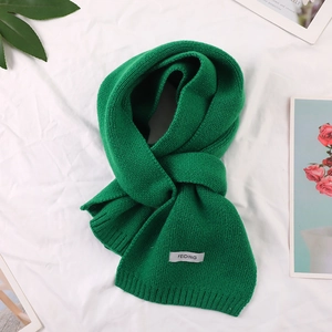 Detailed close-up of green knitted winter scarf with minimalist brand label and soft texture
