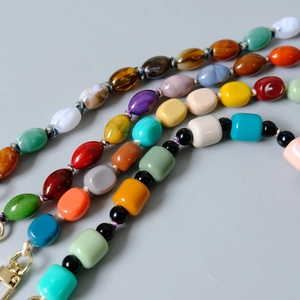 Detail of colorful acrylic beaded chains with gold lobster clasps in macro view