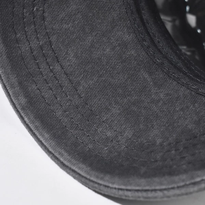 Détail des coutures multiples sur le bord d'une casquette militaire en coton délavé
