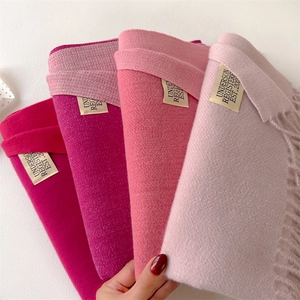 Detail of four gradient pink cashmere-feel scarves showing soft texture and woven labels