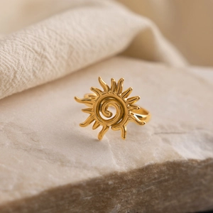 Macro d'une bague spirale soleil en or 18K sur pierre naturelle et tissus doux
