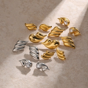 Detailed macro view of gold and silver wave-shaped earrings with clear gemstone inlay