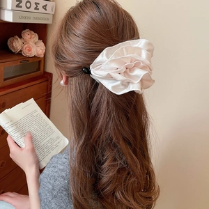 Détail d'une grande pince à cheveux fleur à volants en satin rose doux sur modèle