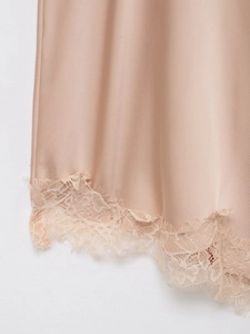Close-up of champagne satin fabric with delicate eyelash lace hem on the dress