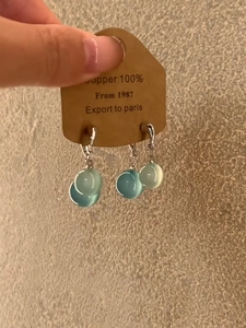 Detailed close-up of water blue teardrop earrings with a copper base and silver hooks