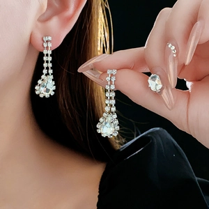 Close-up of elegant silver drop earrings with faceted crystals and pear-shaped pendants
