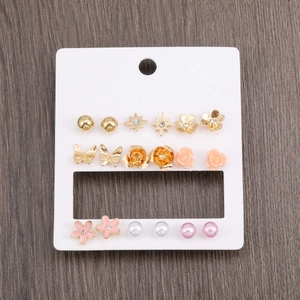 Detailed set of assorted gold-finish stud earrings with floral and pearl designs on display card