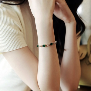 Bracelet plaqué or avec cristaux vert émeraude et zircons porté au poignet