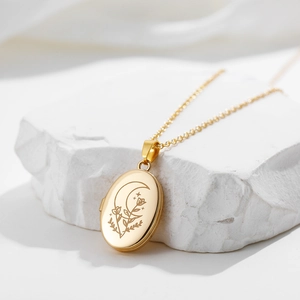Detail of a gold oval locket necklace with celestial moon and star engravings