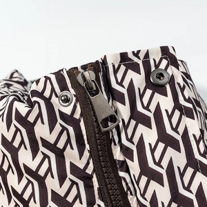 Detail of black and white geometric print jacket featuring bronze metal zipper and snaps