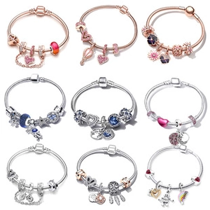 Macro shot of silver and rose gold charm bracelets with intricate enamel and zircon details