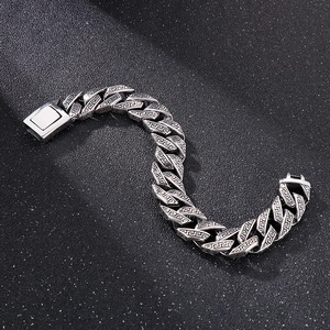 Macro detail of silver Cuban link bracelet with engraved Greek meander patterns