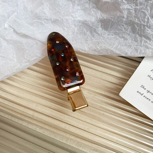 Close-up of amber acrylic hair clip with colorful rhinestones and gold metal base
