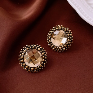Detailed macro view of vintage gold flower stud earrings with brown faceted gemstones