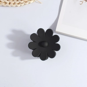 Detailed top view of a matte black flower hair claw clip on a clean white surface