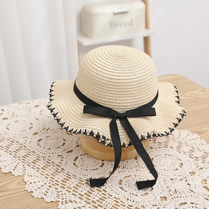 Elegant beige straw sun hat with black bow and scalloped edge for beach vacation