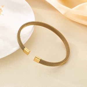 Dettaglio di un elegante bracciale rigido aperto a maglia intrecciata oro placcato 18K