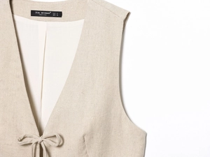 Vue détaillée du gilet en lin beige avec nœud délicat et texture de tissu tissé serré