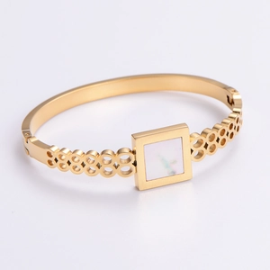 Macro detail of gold geometric hollow cuff bracelet with white square shell inlay