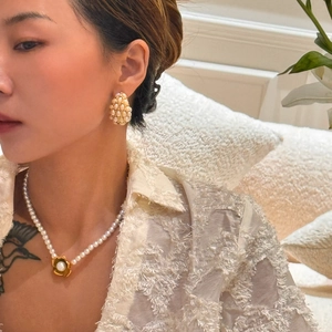 Close-up of vintage hollow water drop earrings with pearls on a model in natural light